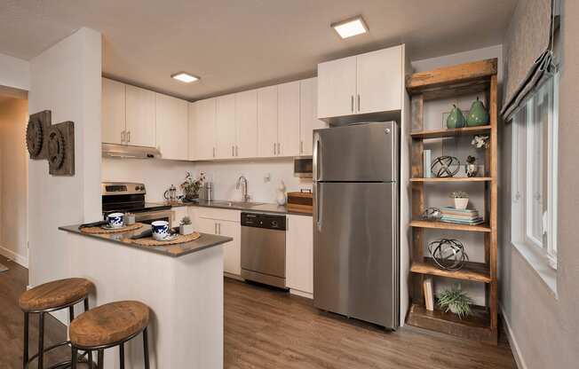 A modern kitchen with a stainless steel refrigerator and wooden bar stools