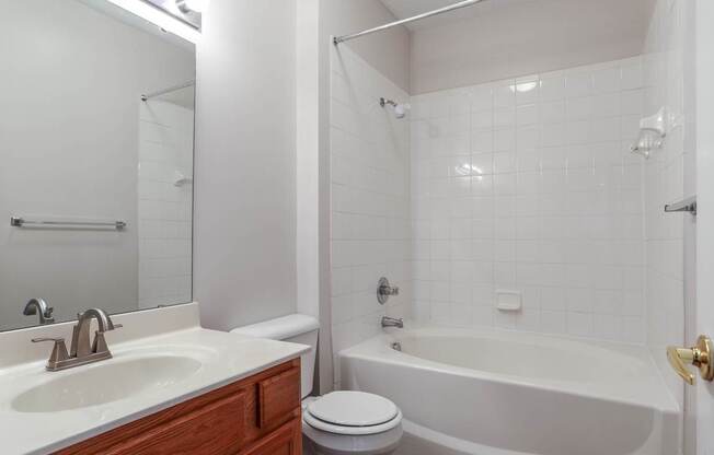 A white bathroom with a toilet, sink, and bathtub.