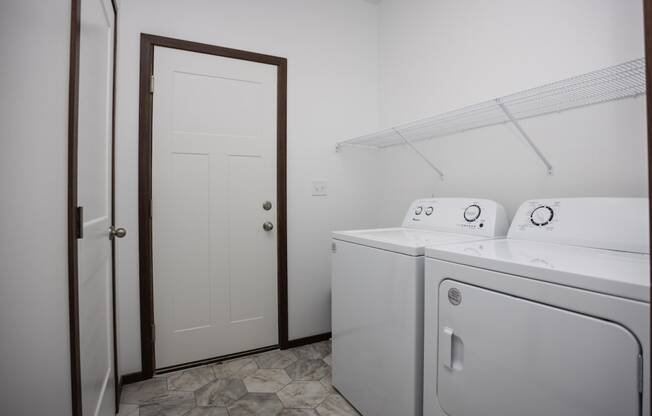 a white laundry room with two washes and a dryer