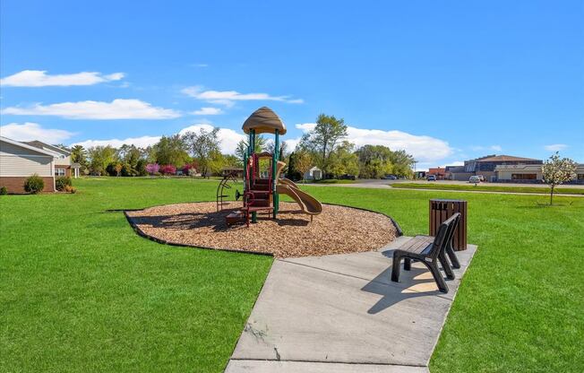 playground and bench in the green space at Muskego School Apartments