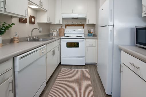 Model apartment kitchen with white appliances and white cabinets