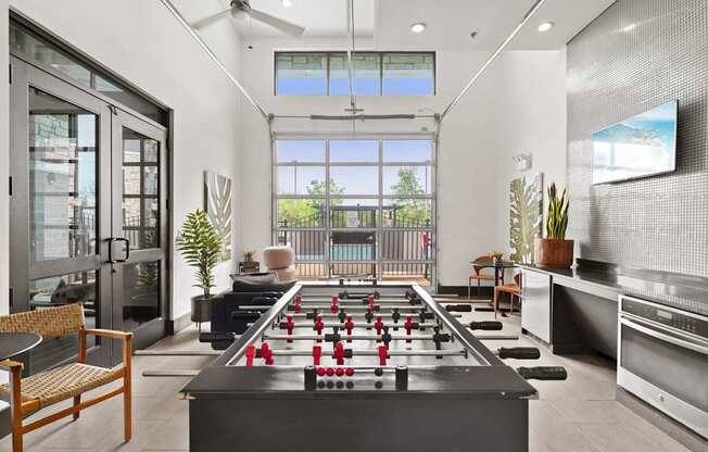 A foosball table is in the middle of a room with a chair and a plant.