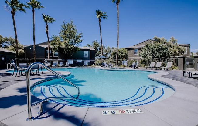 A swimming pool surrounded by palm trees and lounge chairs.