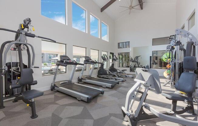 a gym with cardio equipment and windows in a building