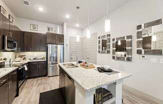 A modern kitchen with dark brown cabinets and stainless steel appliances.