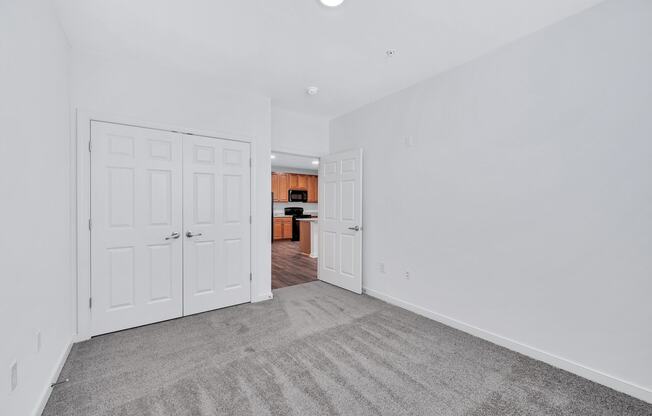 a bedroom with two closets and a door to a kitchen