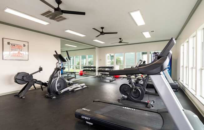 a gym with treadmills and other exercise equipment and windows