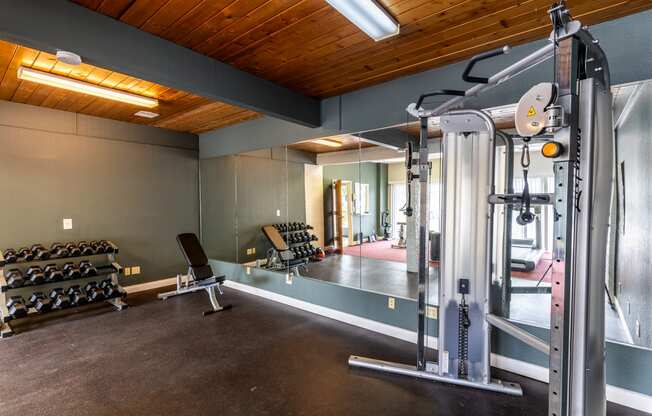 a gym with weights and equipment in a home with a wood ceiling