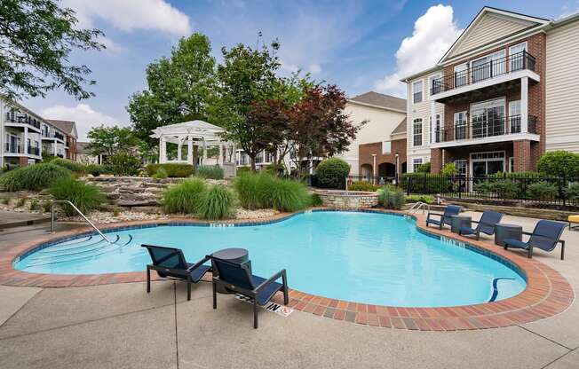 A swimming pool surrounded by chairs and a gazebo in a residential area.