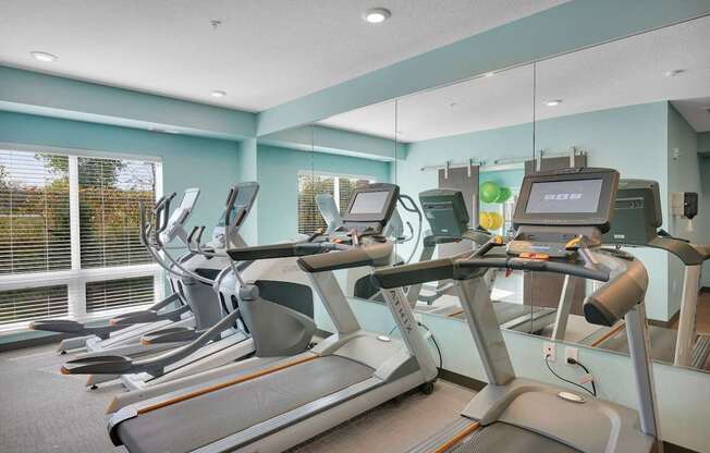 A gym with treadmilers and exercise bikes.