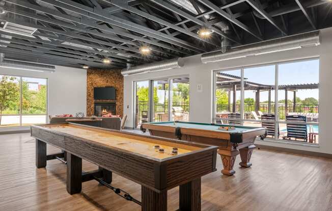 a game room with shuffle board, pool table, and fireplace at TRIO @ Southbridge apartments