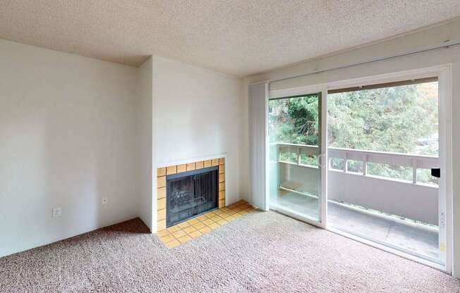 Inviting living room at Heritage Grove Apartments Renton WA with fireplace, large window for natural light, and carpeted flooring.