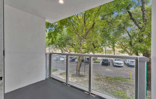 A balcony with a view of a parking lot and trees.