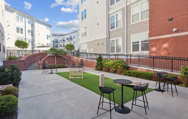 A patio with a table and chairs is surrounded by a brick wall and a metal fence.