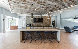 a kitchen with bar stools and a tv in a room with a living room