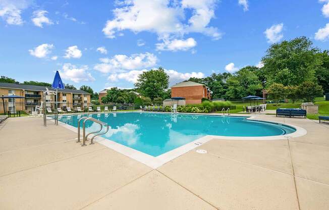 A large outdoor swimming pool with a blue sky and clouds in the background.