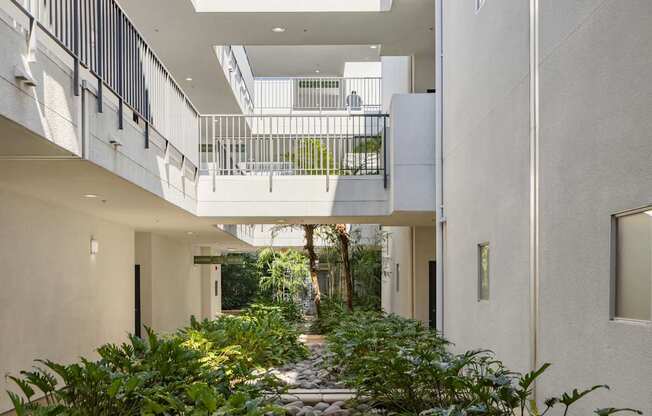 A long pathway with rocks and plants on either side leads to a balcony.