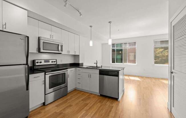 A modern kitchen with stainless steel appliances and wooden floors.