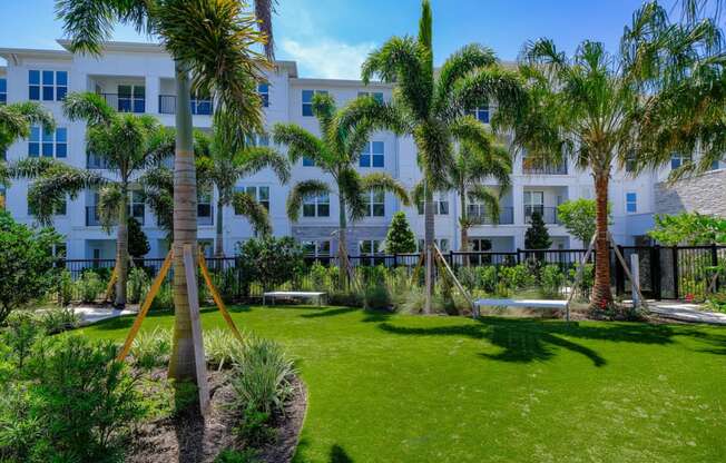 a yard with palm trees in front of a white building at Altis Grand Lake Willis, Orlando, FL 32821