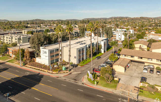 A street view of a residential area with apartment buildings and parked cars.