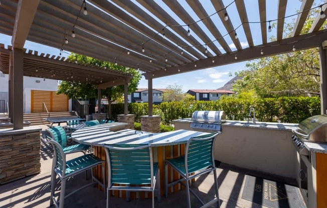 A patio with a table and chairs under a wooden pergola.