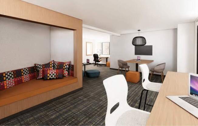 A room with a laptop on a desk and a couch with a blanket on it.