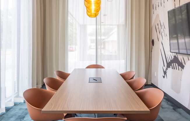 a meeting room with a long wooden table and orange chairs