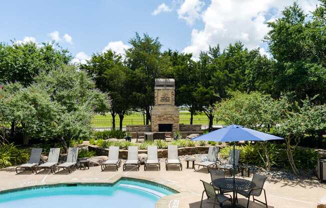 A pool surrounded by chairs and a stone monument.