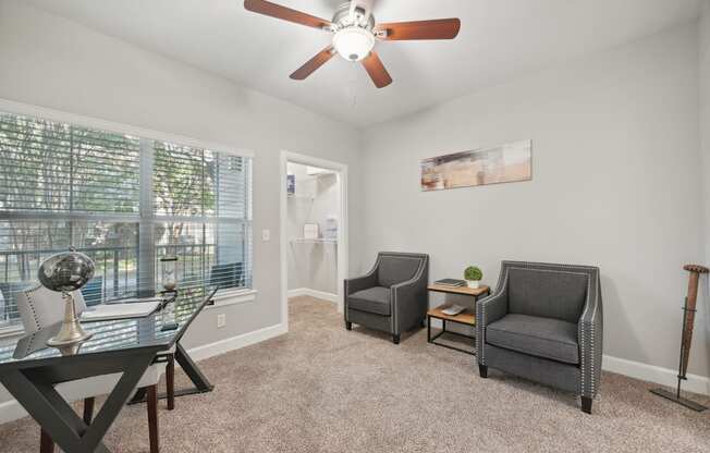 A room with a ceiling fan and three chairs.