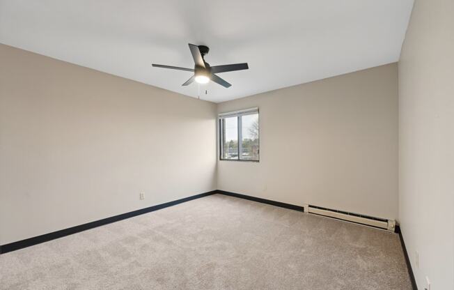 an empty living room with a ceiling fan and a window