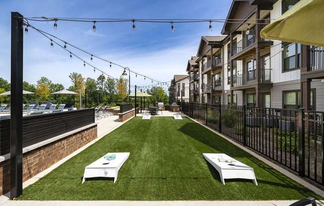 a grassy courtyard with two white tables and a fence