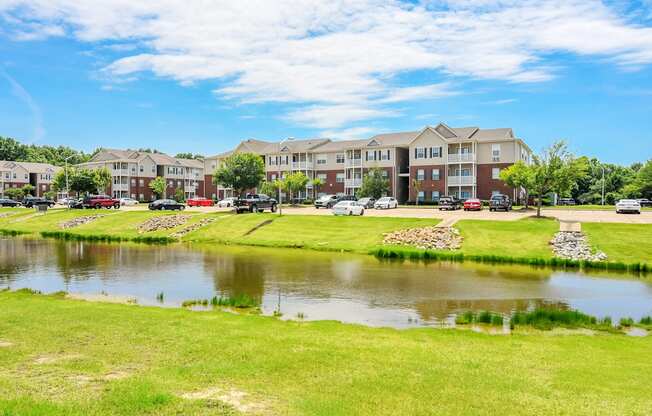 a pond in front of an apartment complex with a lake at Vineyard of Olive Branch in Olive Branch, MS