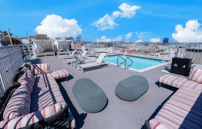 a roof top pool with furniture and a city in the background