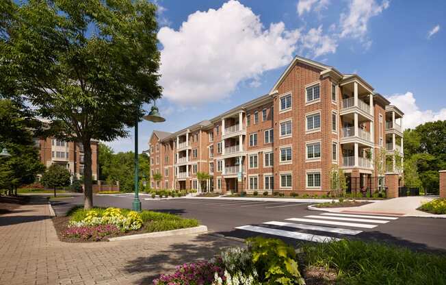 Exterior View of Claremont on the Square 4-story apartment buildings in Exton, PA with nearby resident parking and beautiful trees and flowers.