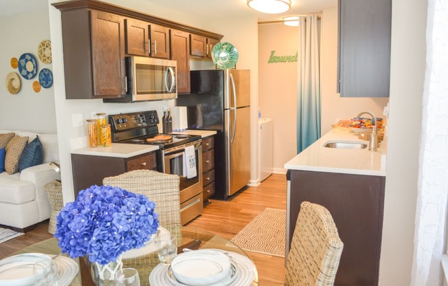 a kitchen with stainless steel appliances and wooden cabinets and a dining table