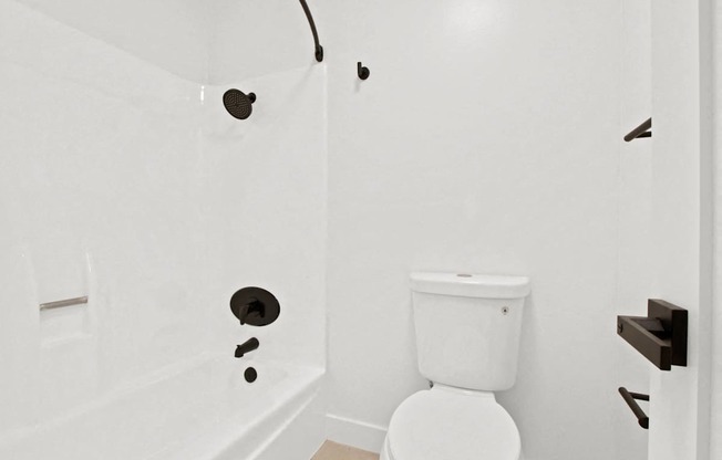 A white toilet in a bathroom with a white tub.