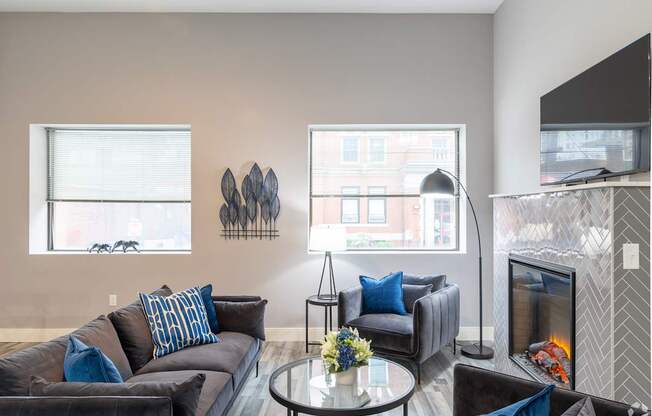 A living room with a grey couch and a fireplace.