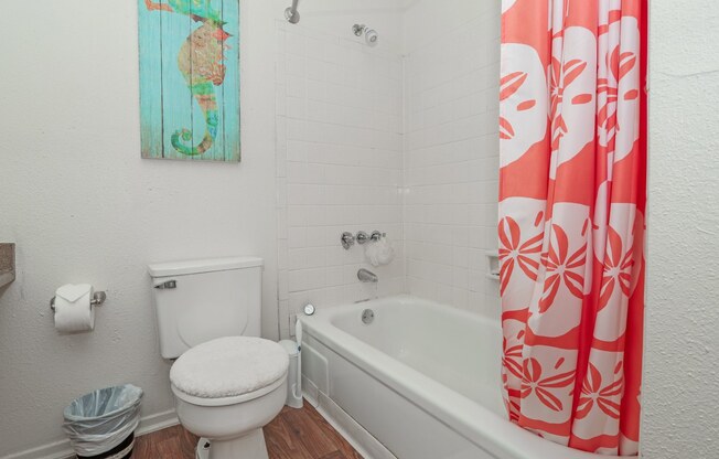 Model bathroom with a white toilet next to a bathtub at Laurel Parc apartments in Shreveport, LA.