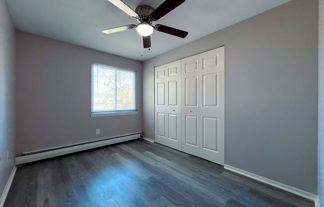 an empty living room with a ceiling fan and a window