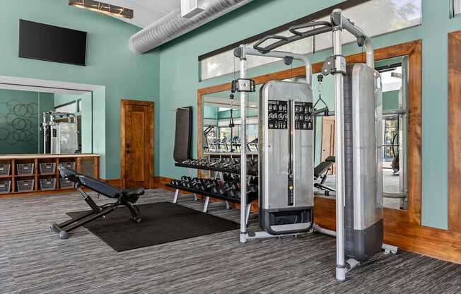 A gym with a variety of equipment including a weight machine and a bench.
