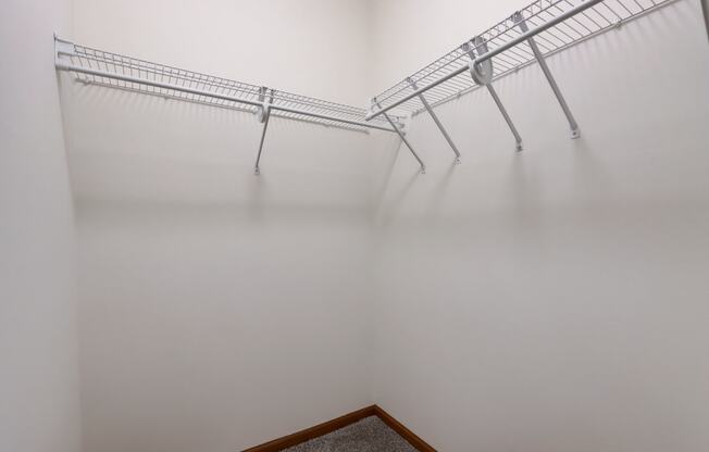 an empty closet with three metal shelves on the wall