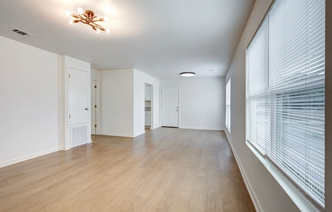 Whitney Manor Apartments in Gretna, LA photo of  an empty living room with a large window and wood flooring