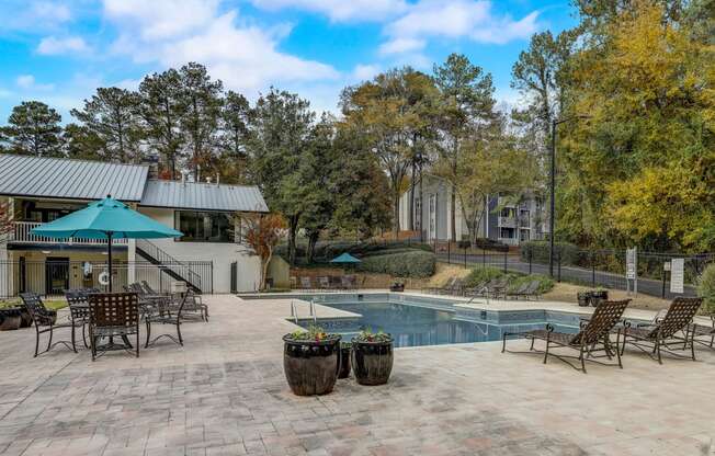 a resort swimming pool with lounge chairs and fall trees at Veridian at Sandy Springs