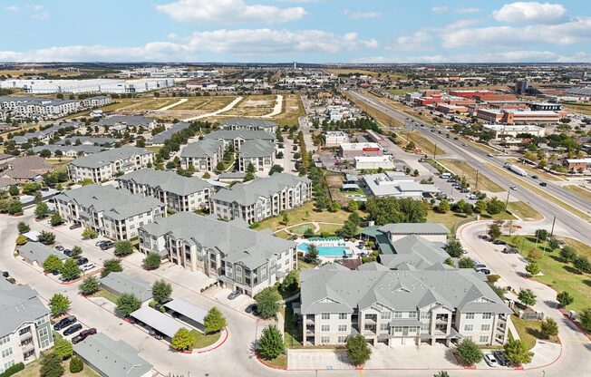 A bird's eye view of a residential area with multiple houses and a swimming pool.