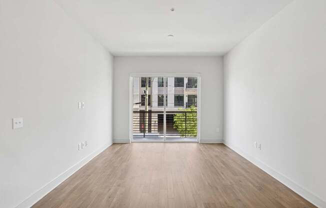 A living and dining room with a large window and wooden flooring in B8 floor plan at Knox Heights in Dallas, TX