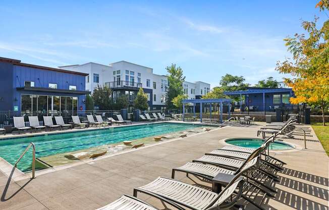 A pool with sun loungers and a building in the background.