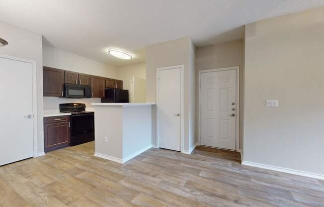 an empty kitchen and living room with a door to the bathroom