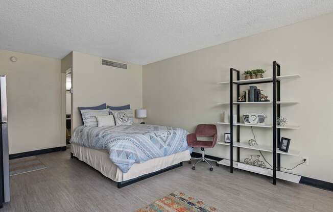 A bedroom with a bed, chair, and shelves.