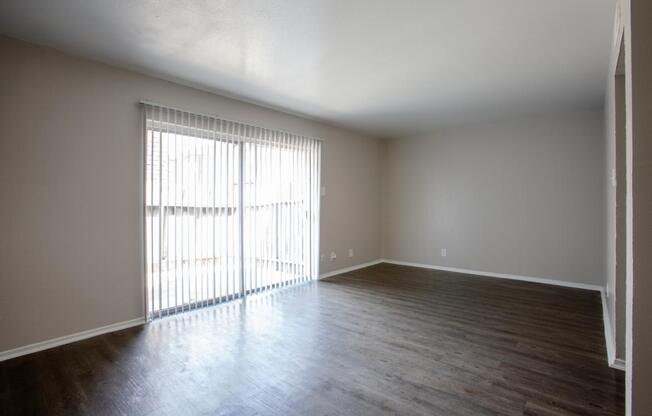 A room with wooden floors and a window with blinds.