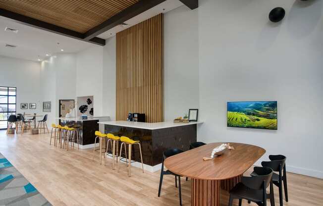 a resident gathering area with a wooden table and chairs and a bar with yellow chairs at Presidio Palms Apartments, Tucson